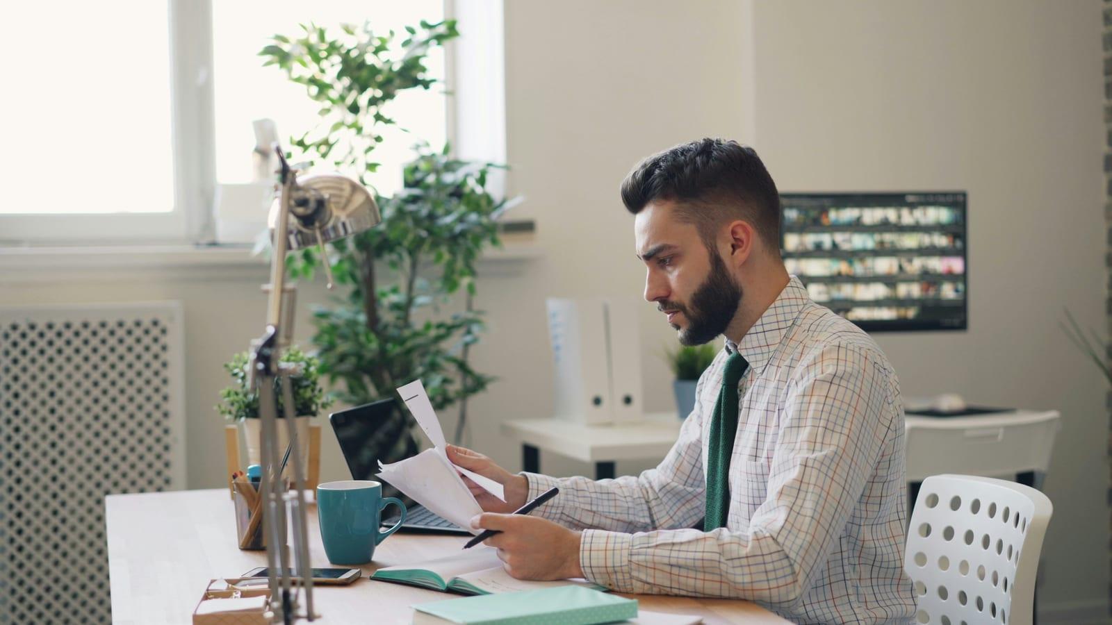 Professional freelancer reviewing an invoice on a laptop at a clean modern desk.
